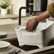 Afwasteil Wash & Drain van Joseph Joseph beige die gevuld wordt met water van de kraan