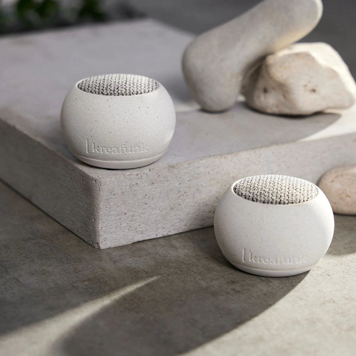 Draagbare Bluetooth speaker Ago Stone van Kreafunk natural buiten tussen witte stenen