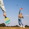 Beach tennisset veelkleurig in 2 racketten en 2 zwarte balletjes gespeeld door twee personen waarvan er één in de lucht springt