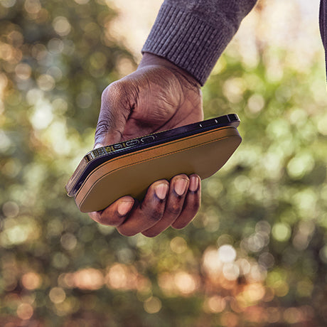 Draadloze powerbank Softpower van Lexon bruin met iPhone er op in de hand gedragen