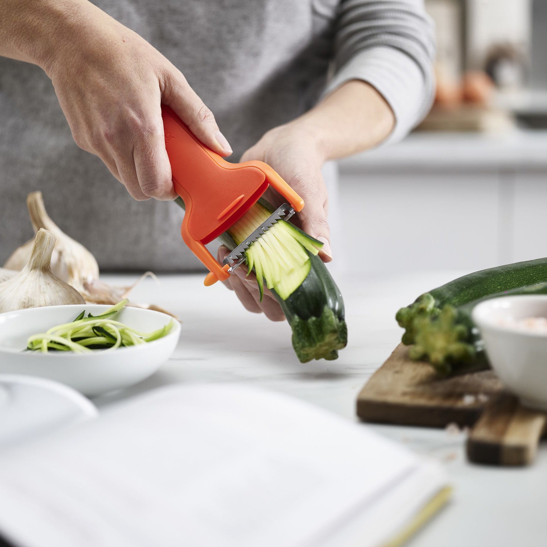 Oranje dunschiller julienne snijder Safestore van Joseph Joseph die courgette snijdt