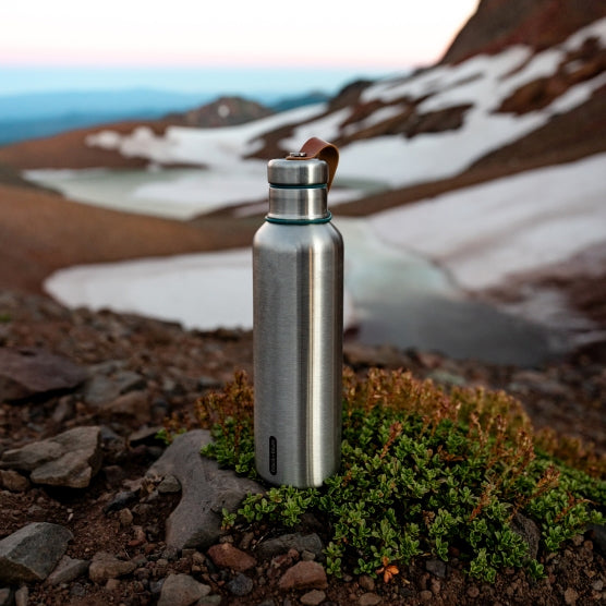 Stainless Steel drinkfles van Black&Blum met dop met groene rand en leder draagbandje in een landschap met besneeuwde rivier