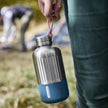 Stainless steel drinkfles van Black & Blum met Ocean Blue onderkant gedragen door een vrouw op de camping