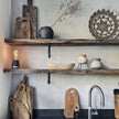 Humble One lamp dark gray in een hoek op een houten plank tussen houten kunstwerken