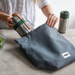 Stainless Steel Food Flask van Black & Blum dat in een draagtas gestoken wordt door een dame