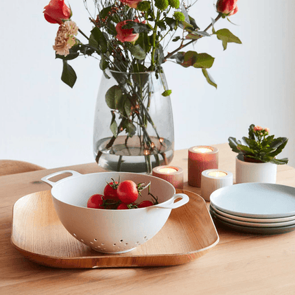 Vergiet van 23 cm uit PLA lichtgrijs van Point-Virgule gevuld met tomaten op een houten tafel met bloemen